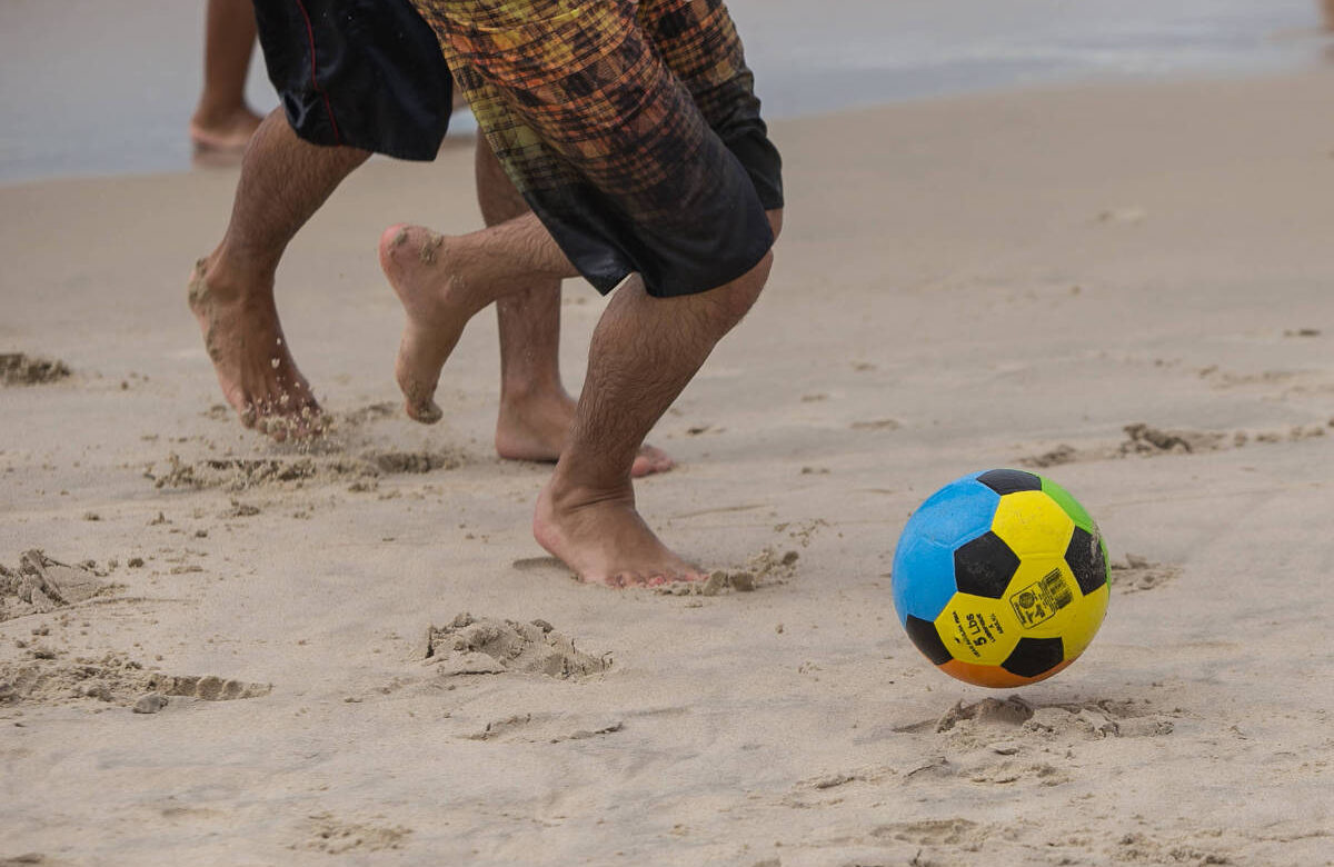 Adolescentes jogam bola na praia de Maresias, litoral norte de São Paulo