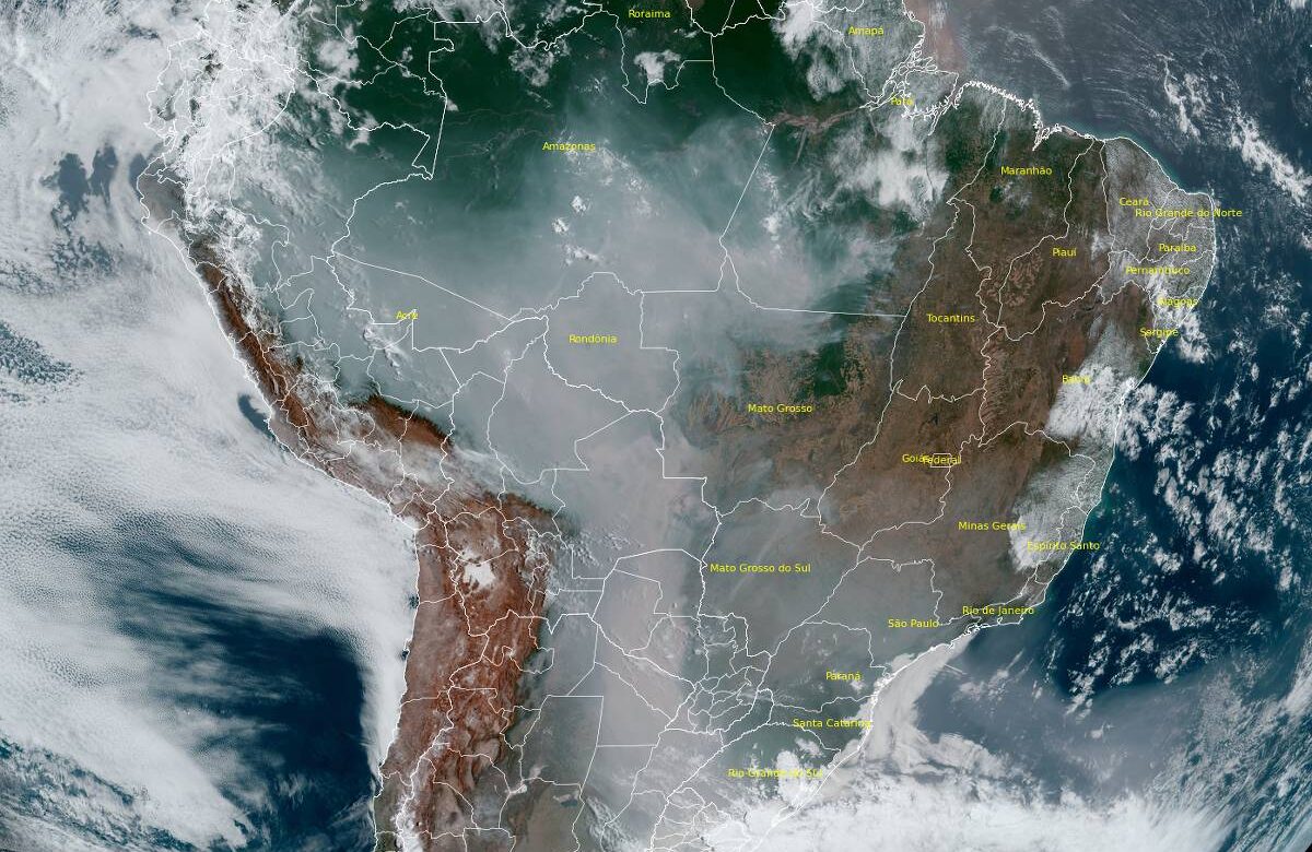 A imagem mostra uma vista de satélite da América do Sul, destacando a geografia do continente. É possível observar áreas de vegetação densa, nuvens e uma parte do Oceano Pacífico à esquerda. A imagem apresenta uma mistura de terra e água, com algumas áreas cobertas por fumaça ou neblina.