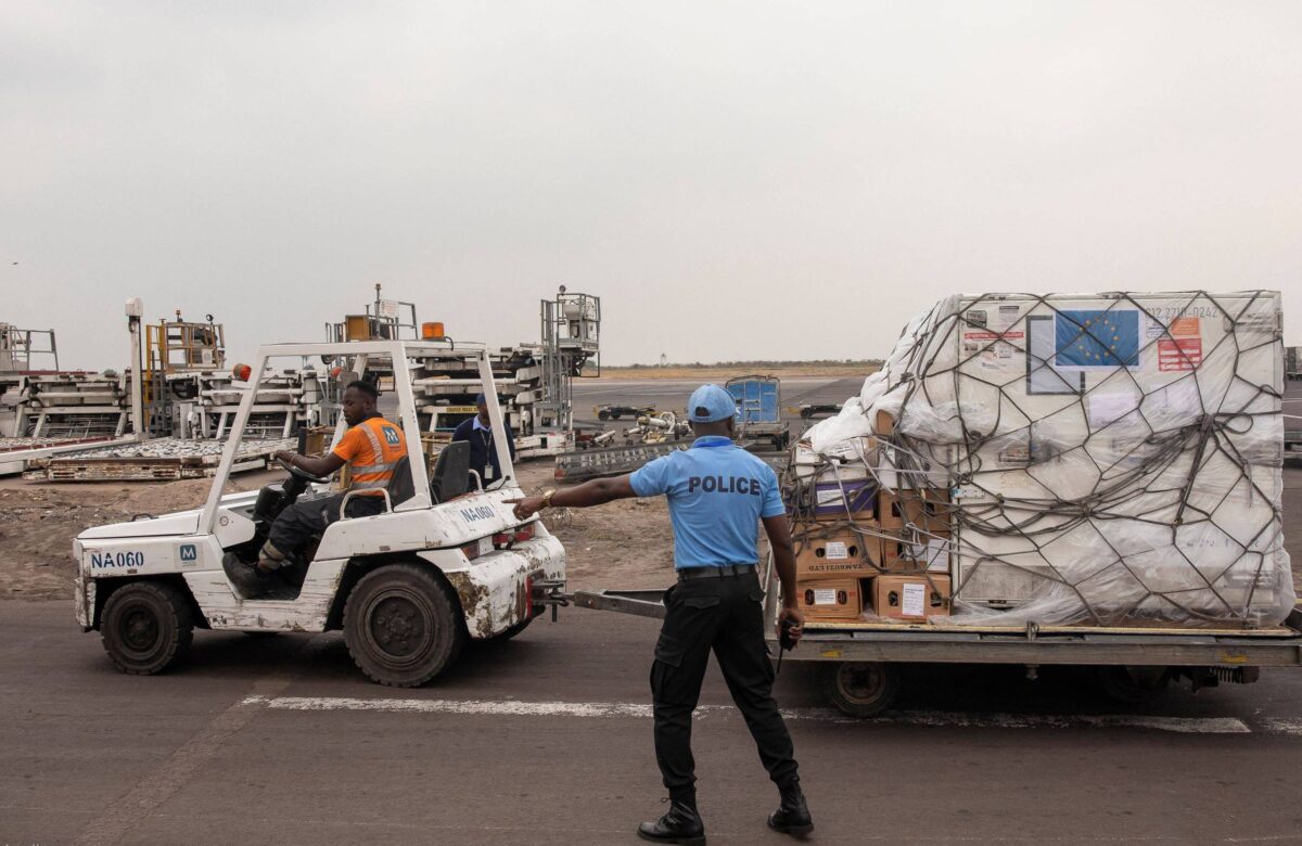 Policial gesticula para o motorista de um veículo que carrega um lote de vacinas contra mpox na pista do Aeroporto Internacional de Kinshasa, no distrito de Nsele, em Kinshasa, na República Democrática do Congo