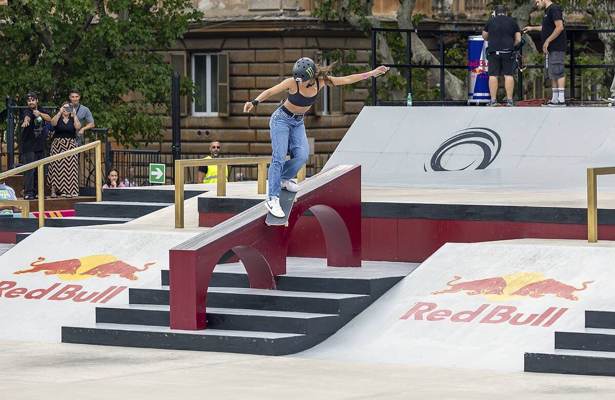 Rayssa Leal desce uma rampa com o skate. Ela usa calça jeans, um top preto e capacete