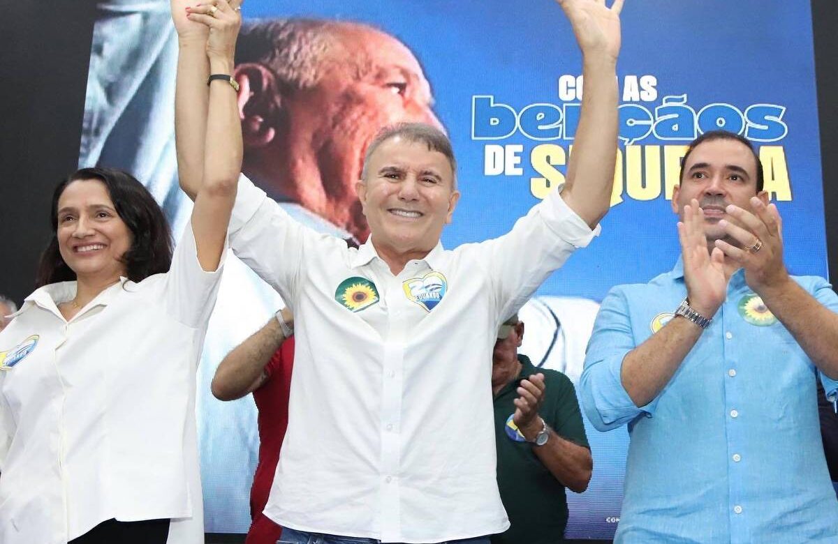 Imagem mostra Eduardo Campos de camisa branca, braços levantados, junto a apoiadores em evento de campanha